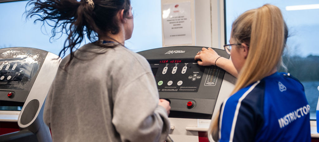 Member being shown a treadmill in the gym